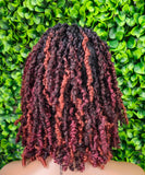 Person with styled hair against a green leafy background