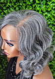Gray wig on a mannequin head with a green leafy background