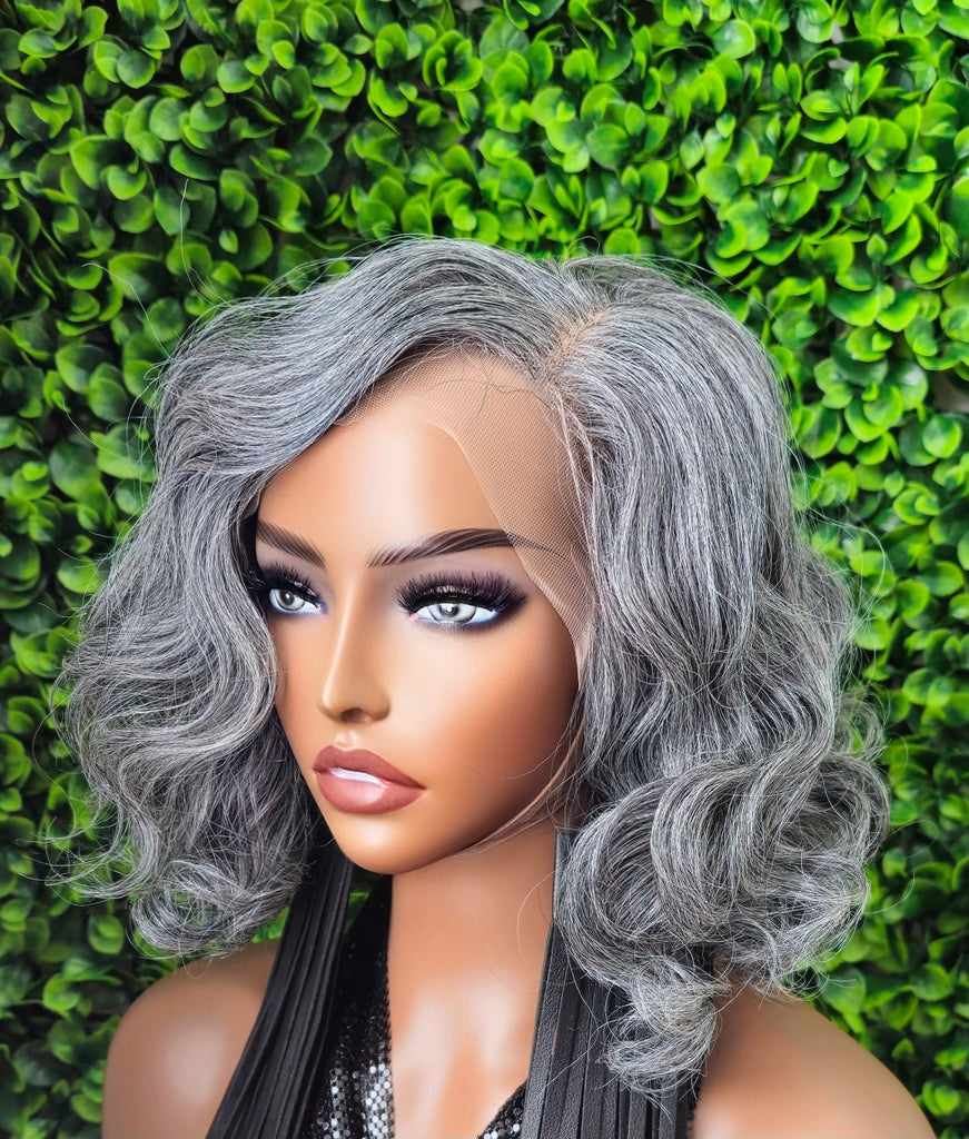 Gray wig on a mannequin head against a green leafy background