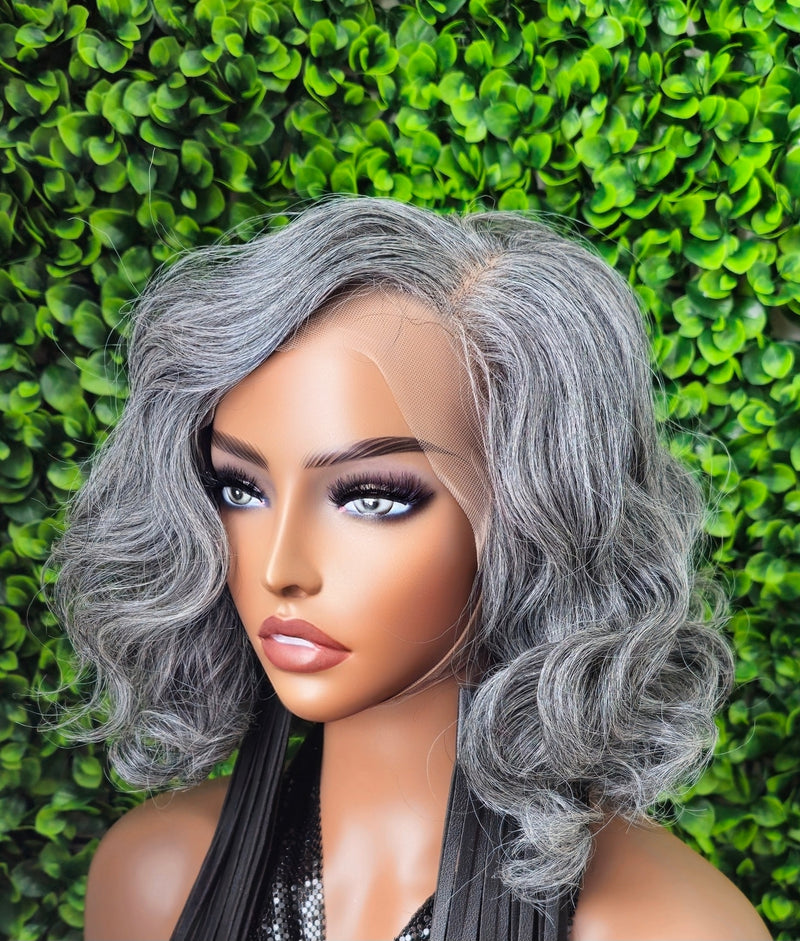 Gray wig on a mannequin head against a green leafy background
