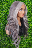 Mannequin head with gray and black ombre wig against a green leafy background